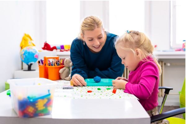 woman helping child with an activity